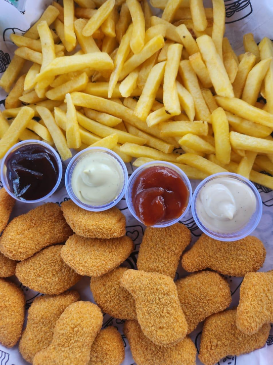 Porção de nuggets e batata frita com molhos