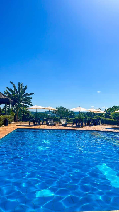 Piscina azul com ombrelones e área de lazer